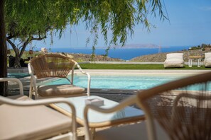 Un espace aménagé au bord de la piscine, avec des chaises longues et une vue sur la mer.