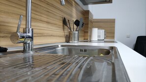 Cozinha moderna com pia de aço inoxidável, painel de backsplash de madeira e micro-ondas.
