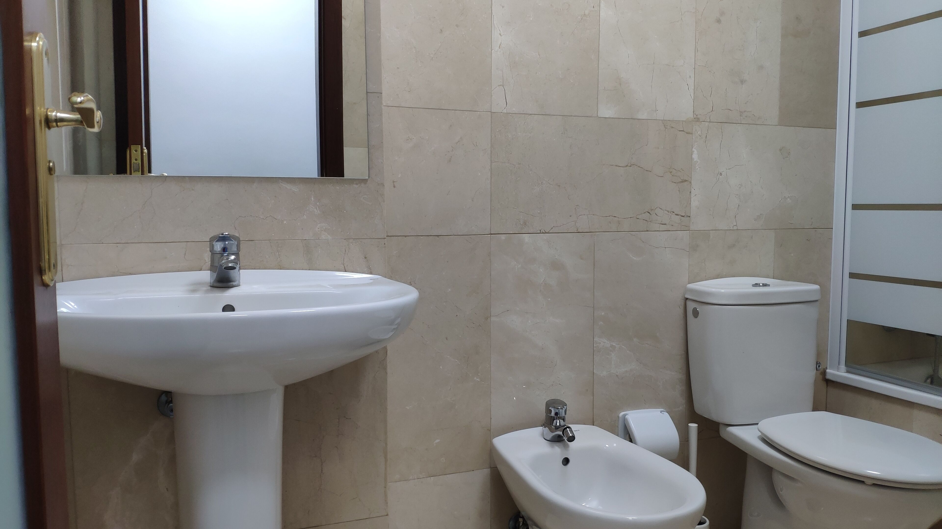 A bathroom with a white sink, a bidet, and a toilet.