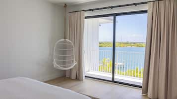 Un dormitorio con cama, un sillón colgante y un balcón con vista al mar.