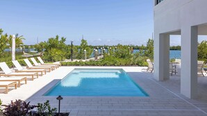 A pool area with lounge chairs and a view of the sea. - The Sunray Home at Lunara Bay (Key West)