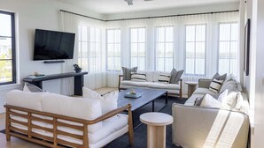 A modern living room with a sofa set, a coffee table, and a TV mounted on the wall. - The Sunray Home at Lunara Bay (Key West)