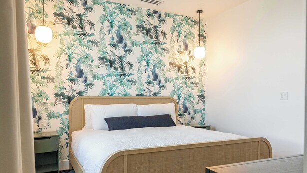 A room with a bed, a desk, and a wall with a leafy pattern. - The Sunray Home at Lunara Bay (Key West)
