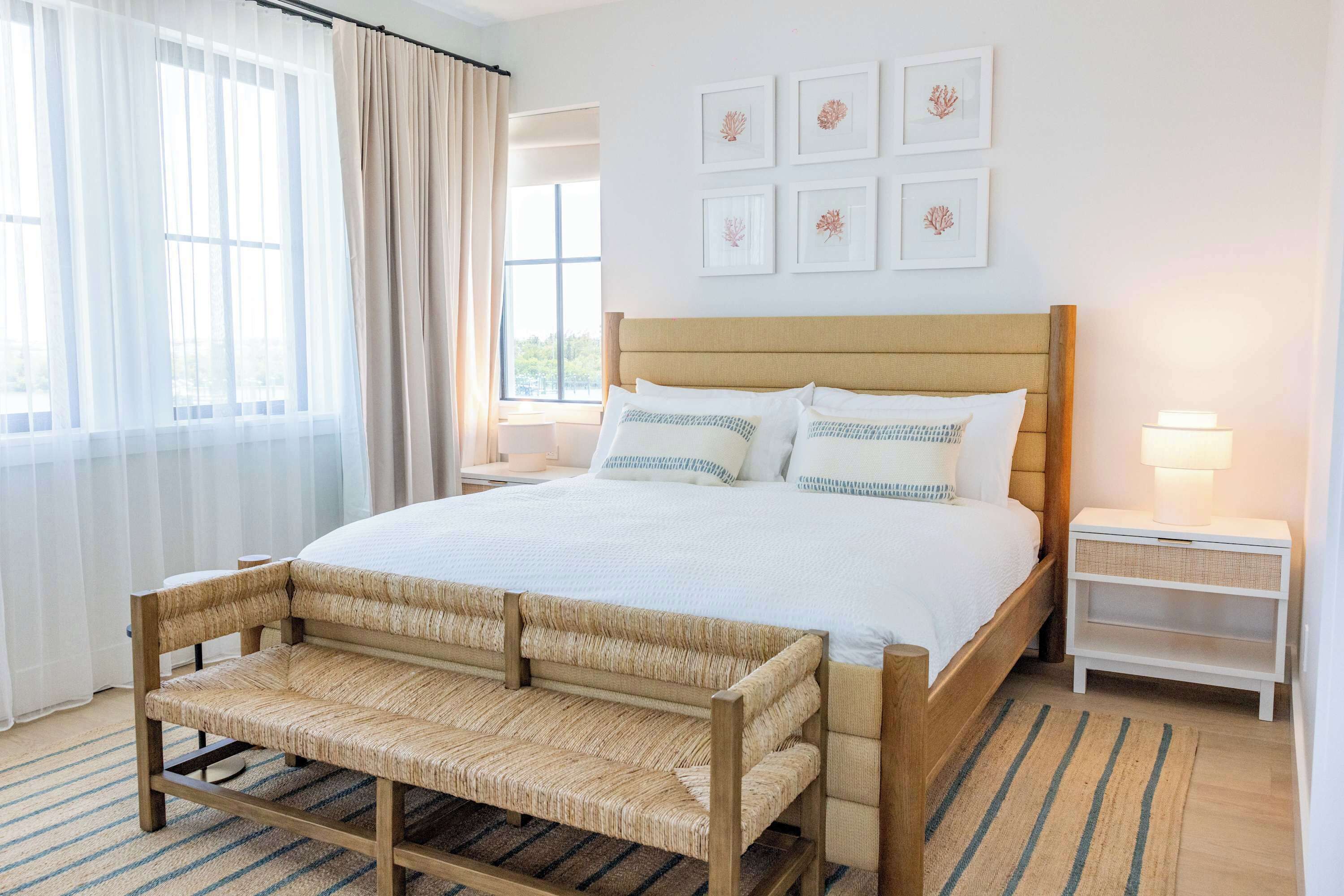 A bedroom with a bed, bedside tables, a bench, and artwork on the wall.