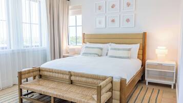 A bedroom with a bed, bedside tables, a bench, and artwork on the wall.