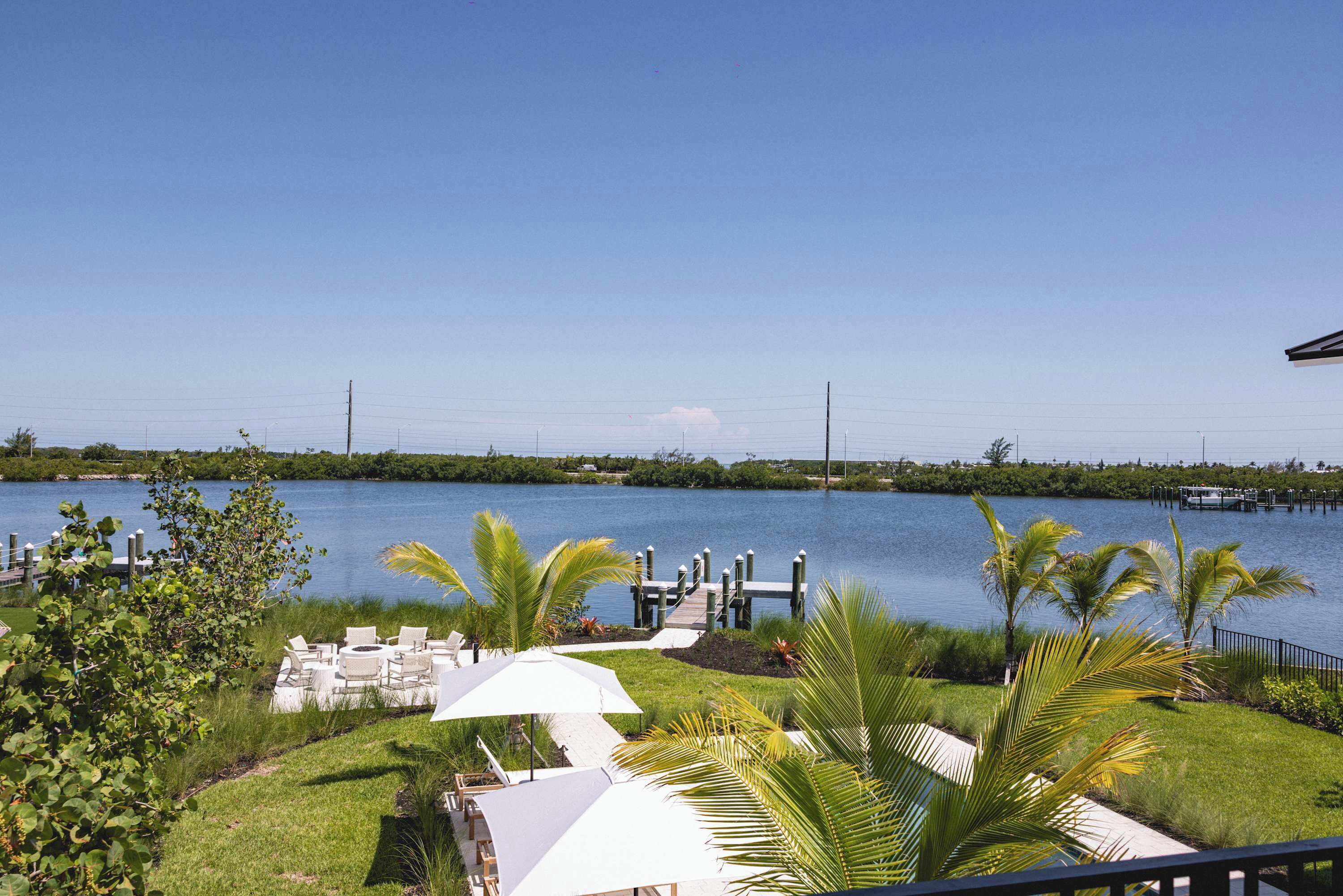 A waterfront property with a dock, outdoor seating, and lush greenery.