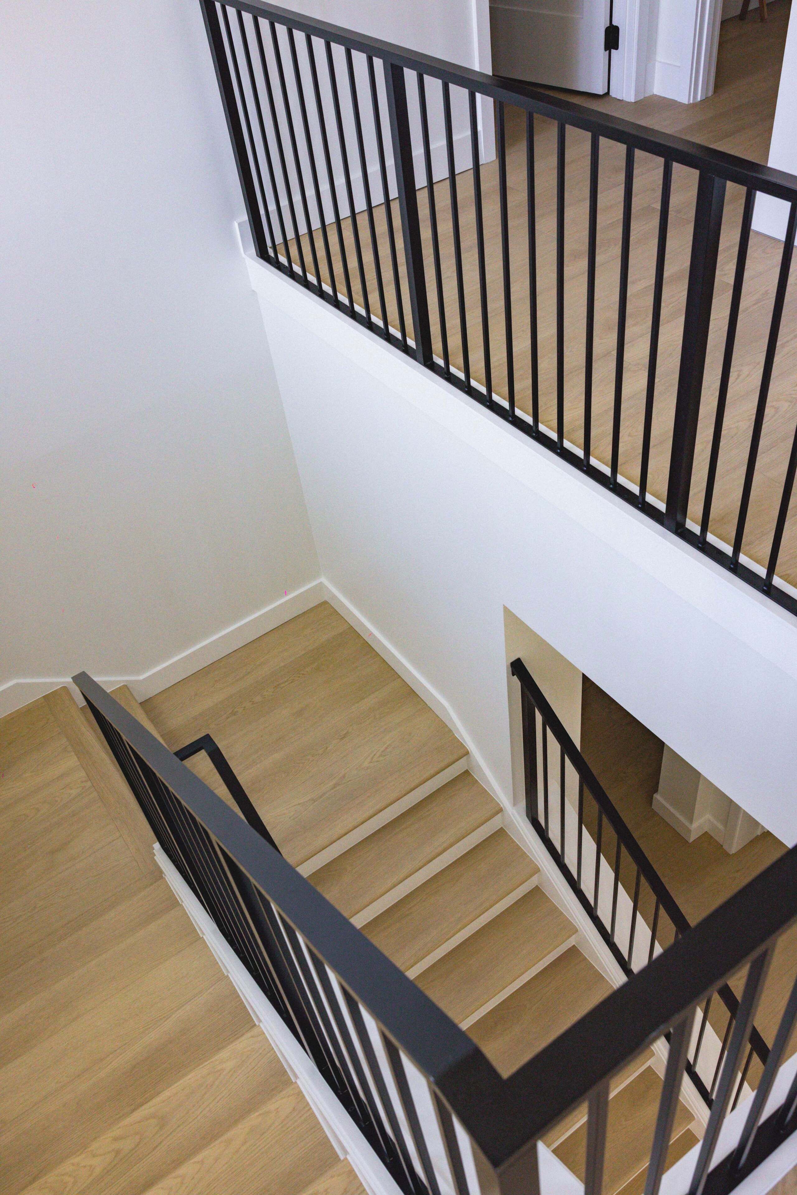 Un escalier avec des rampes noires et des marches en bois.