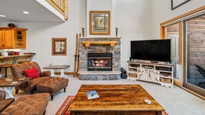 A living room with a stone fireplace, a television, and a wooden coffee table.