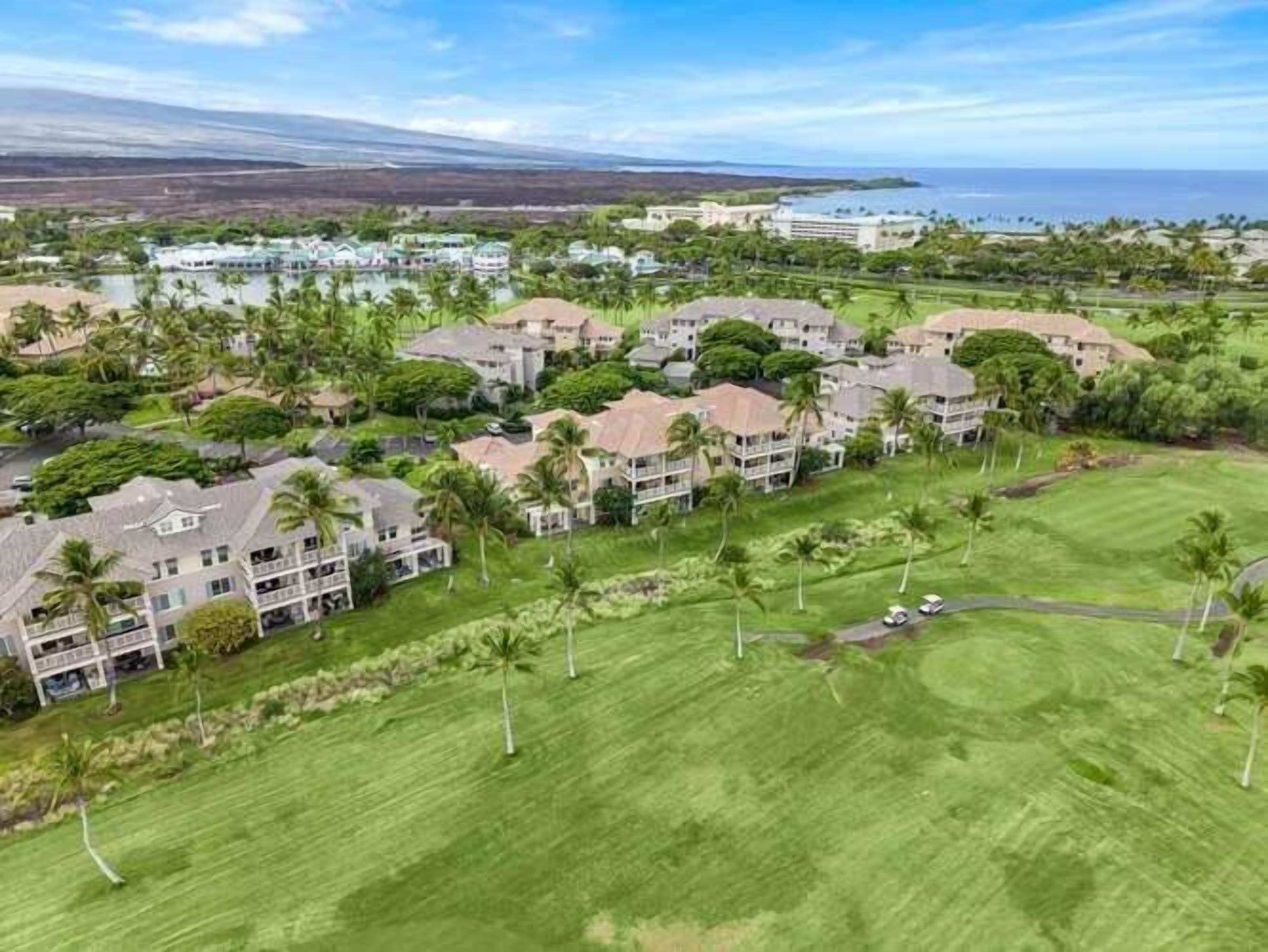A coastal resort with multiple two-story buildings, a golf course, and a view of the ocean.
