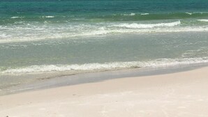Une plage à l’eau turquoise et limpide, bordée d’un rivage sablonneux.