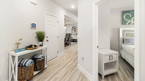 Un couloir avec une console blanche, des paniers en osier et un panneau d’accueil.
