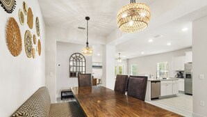 Un espace repas moderne avec une table et des chaises en bois, un banc et des œuvres d’art décoratives murales.