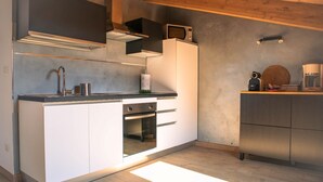 A modern kitchen with white cabinetry, a built-in oven, a microwave, and a coffee maker. - Il Ciliegio Relax & Wellness, apartment surrounded by greenery (Druento)