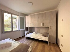 A modern bedroom with a bed, a bench, and a wardrobe. - Ema Home - nature and Lake Como (Argegno)