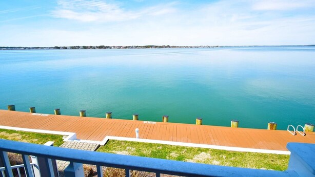 A waterfront view from a balcony with a wooden deck and metal railings. - Harbour Island 103l 2 Bedroom Condo (Ocean City)