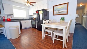 A modern kitchen with white cabinets, a black refrigerator, and a dining area with a table and chairs. - Sea Raider Iv 303 3 Bedroom Condo (Ocean City)