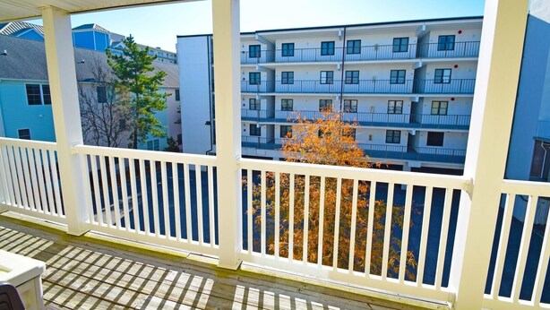 A covered balcony with white railings, overlooking a multi-story building with balconies. - Sea Raider Iv 303 3 Bedroom Condo (Ocean City)