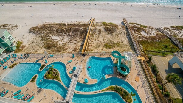 A beach resort with a large swimming pool, a water slide, and a beach area.