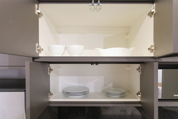 A kitchen cabinet with two shelves, each holding white bowls and plates. - Esquina Pinheiros (Sao Paulo)