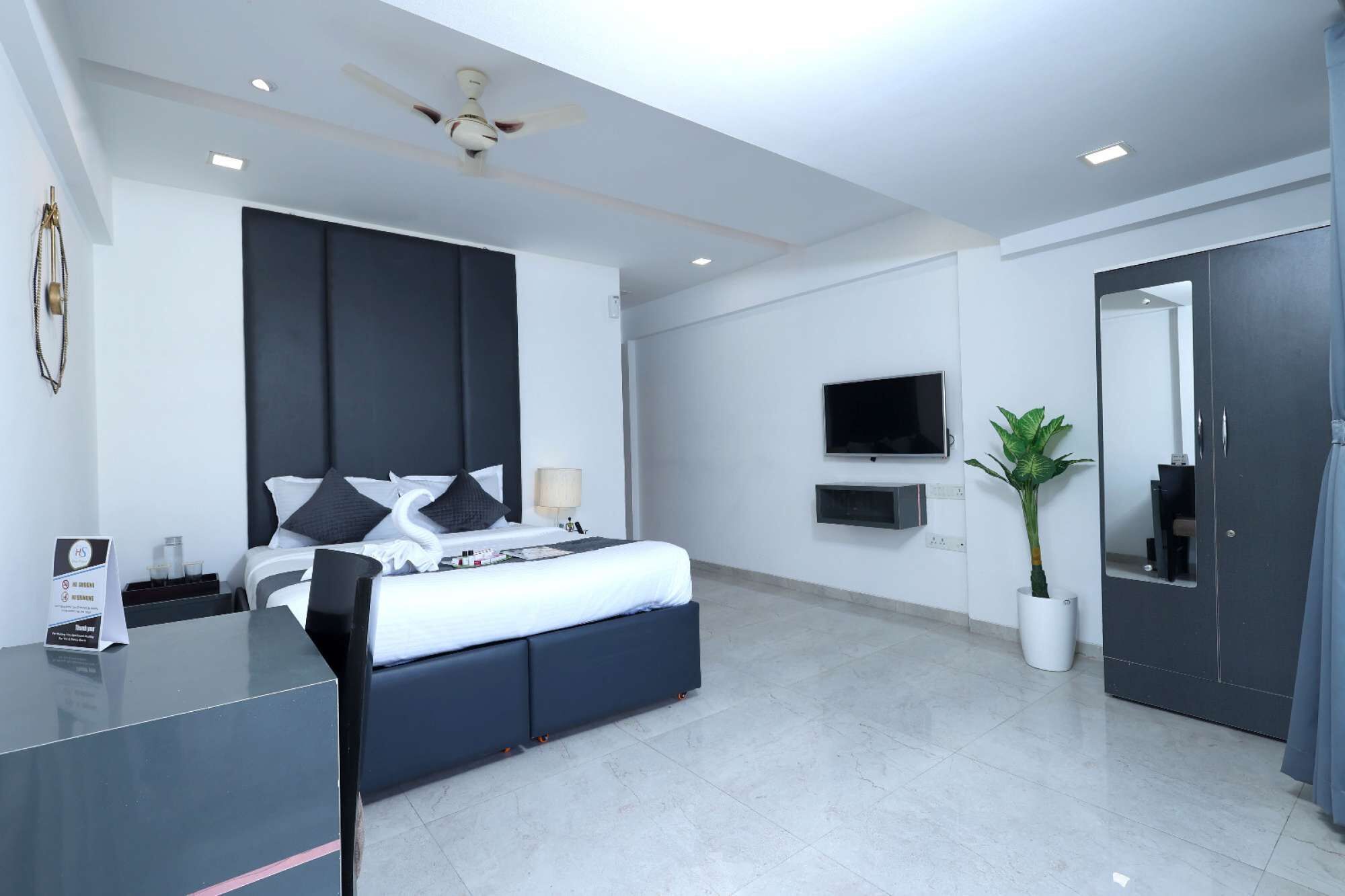 Habitació d'hotel moderna amb llit, escriptori i ventilador de sostre.