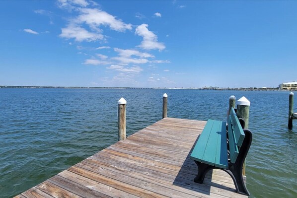 Un muelle de madera que se adentra en aguas tranquilas, con un banco al final.