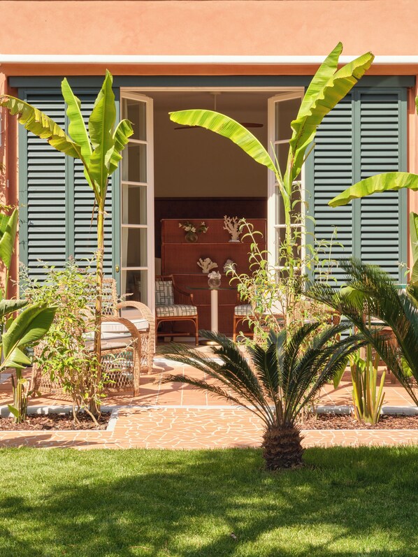 Een huis met een patio, een eettafel met stoelen en diverse planten.