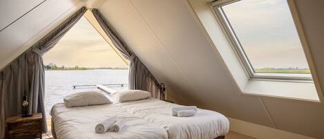 Un dormitorio con una cama grande, una ventana y vistas a un cuerpo de agua.