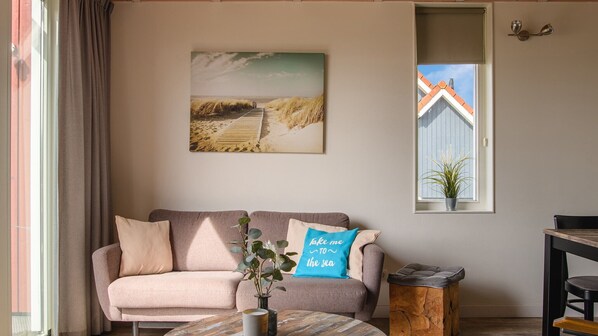 A cozy living room with a sofa, a coffee table, and a painting of a beach scene. - Dormio Waterpark Langelille (Langelille)