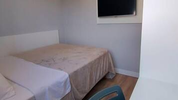 A small, sparsely furnished room with a single bed and a window.