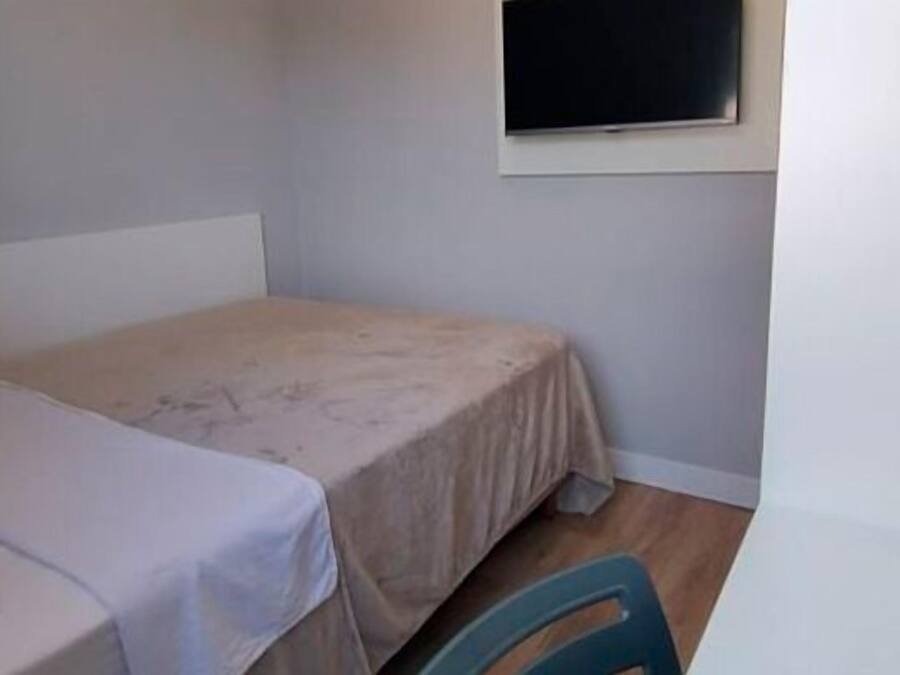 A small, sparsely furnished room with a single bed and a window.