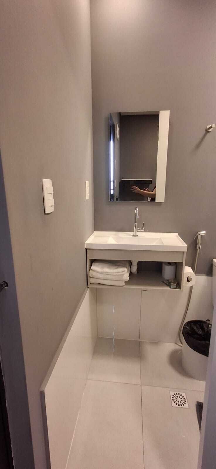 Et lille badeværelse med en hvid vask, et spejl og et toilet.