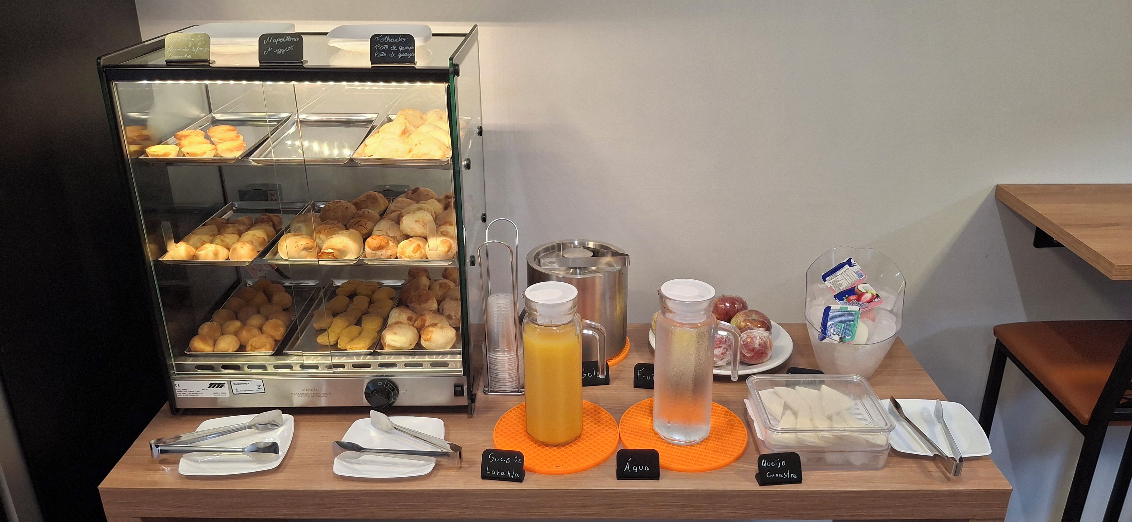 Un bufé de desayuno con diversos pasteles, una máquina de café y una selección de bebidas.