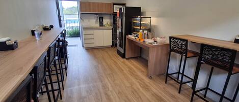 A modern kitchen with wooden countertops, a built-in oven, and a refrigerator. There are bar stools and a small bar area.