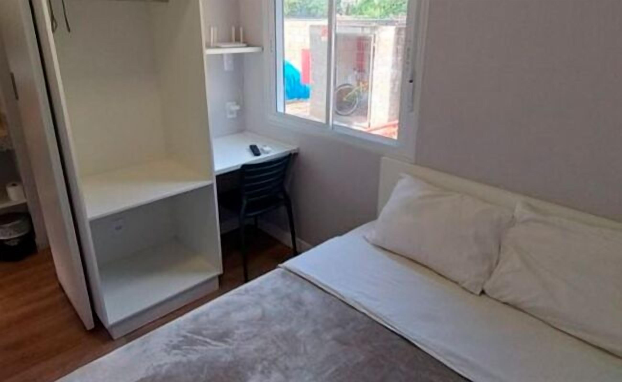 Un dormitorio con cama, escritorio y ventana.