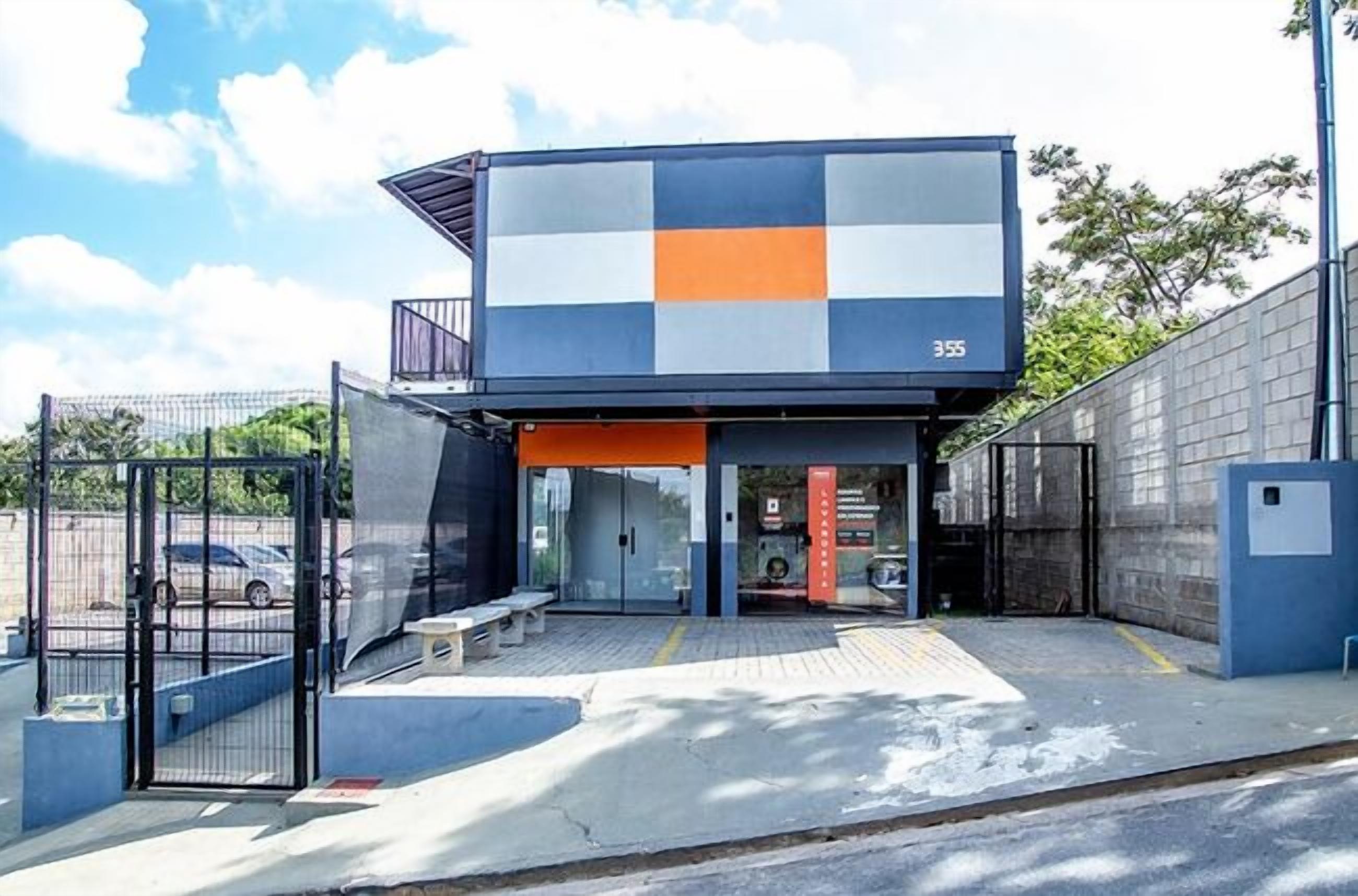 A modern building with a checkered facade, a covered entrance, and a parking area.