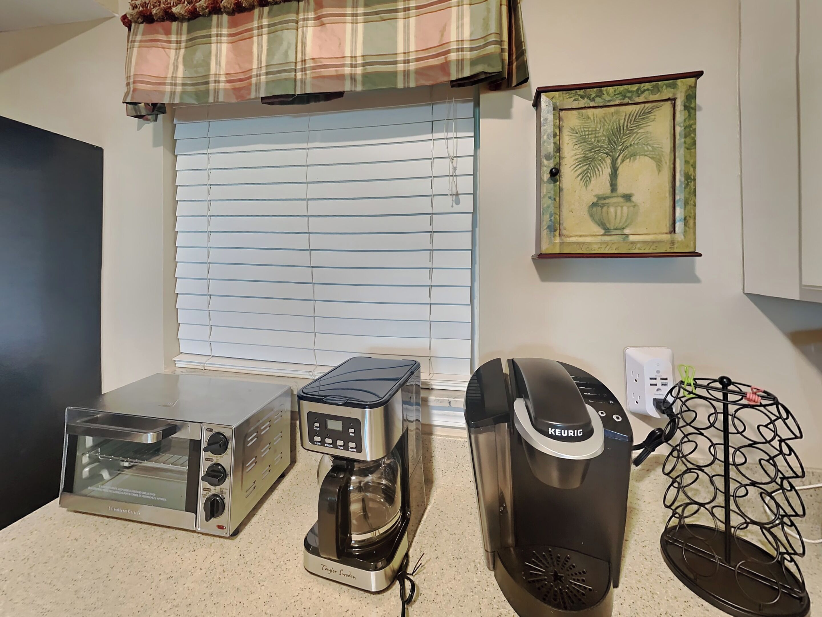 A kitchen with a toaster, coffee maker, and kettle on the counter.