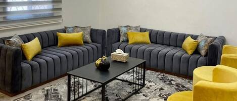 A modern living room with a sectional sofa, a coffee table, and yellow armchairs.