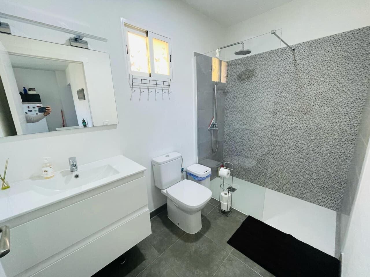 Een moderne badkamer met een wit wastafel, toilet en douche.