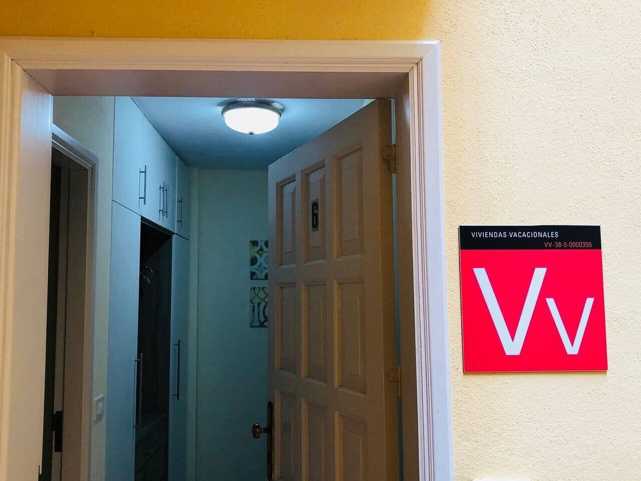 A hallway with a door marked 'Vv' and a sign indicating 'Viviendas Vacacionales'.