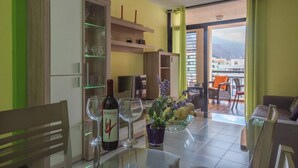 A dining area with a table set for two, a bottle of wine, and a vase with flowers. - Casa Angel - Puerto Naos (Puerto de Naos)