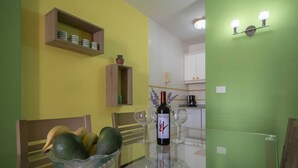 A dining area with a glass table, chairs, a bowl of fruit, and a bottle of wine. - Casa Angel - Puerto Naos (Puerto de Naos)