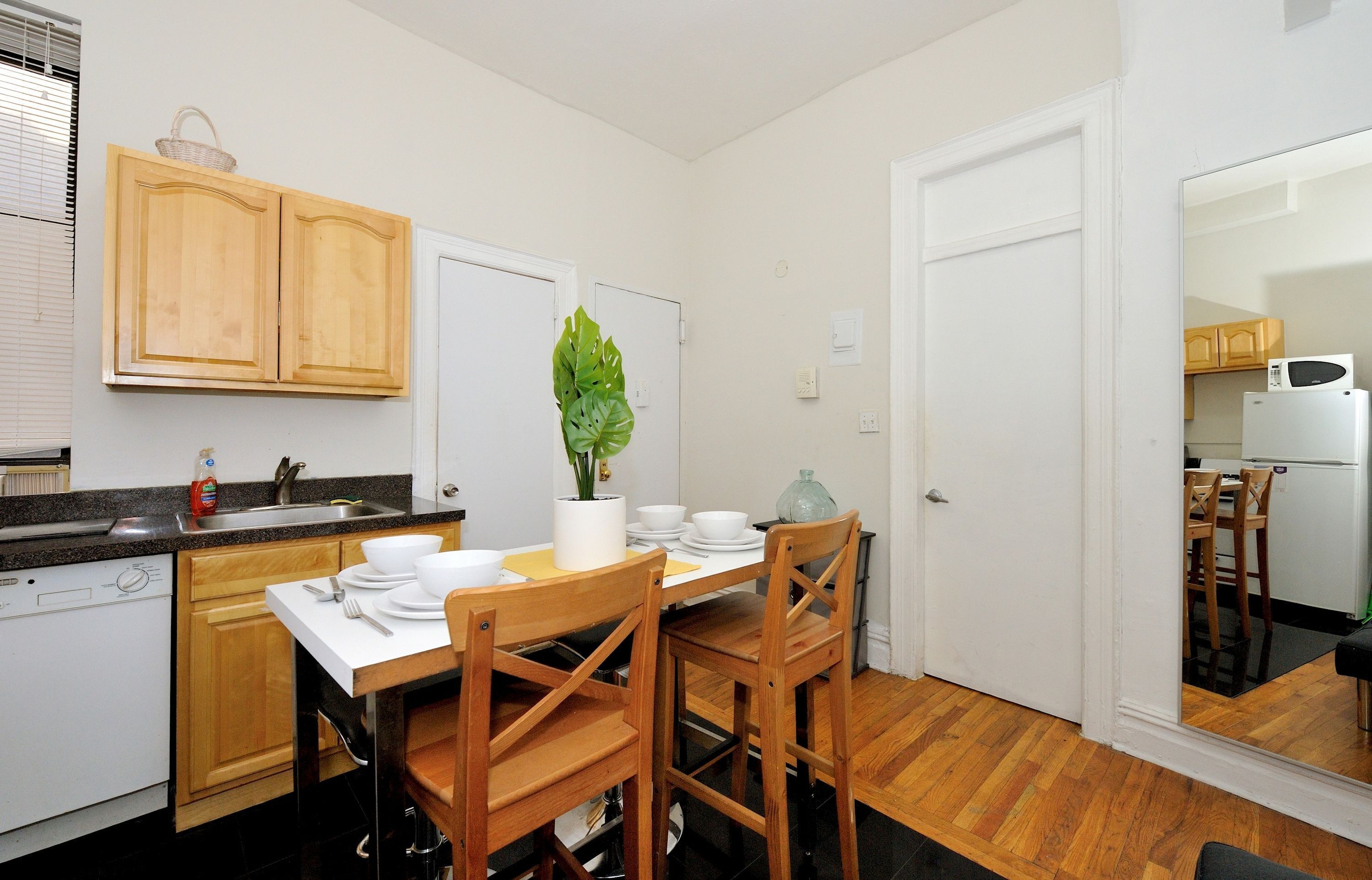 A compact kitchen with wooden cabinets, a sink, and a dining table set for two.