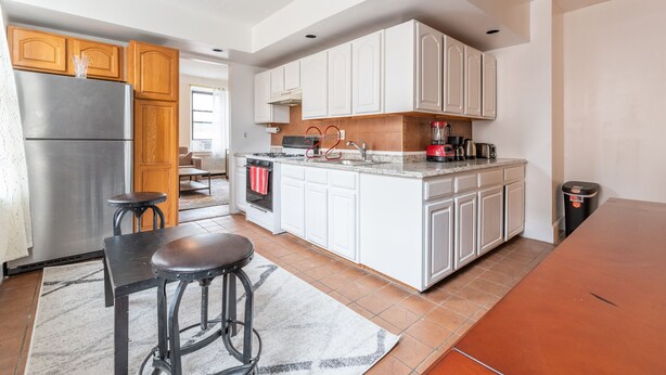 A modern kitchen with white cabinets, a stainless steel refrigerator, a coffee maker, and a sink. - 5 Bedroom 2 Bath Full Floor Midtown (New York)