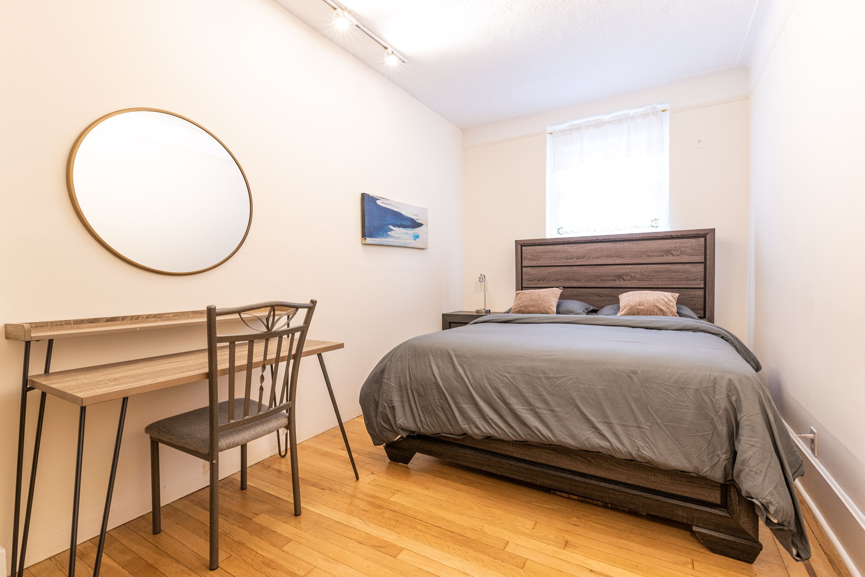 A bedroom with a bed, a desk, and a chair.