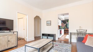 A living room with a TV, sofa, coffee table, and a patterned rug. - 5 Bedroom 2 Bath Full Floor Midtown (New York)