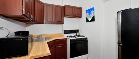 A kitchen with wooden cabinets, a stove, a microwave, and a refrigerator.