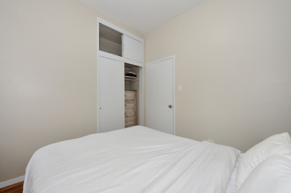 A bedroom with a bed, a wardrobe, and a door leading to a closet. - Charming 1BR in Murray Hill Kips Bay - Perfect for 2 (New York)