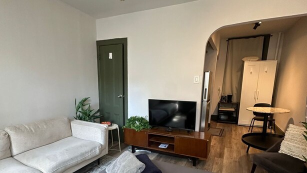Ein modernes Schlafzimmer mit einem Bett, einem Fernseher, einer Couch und einem kleinen Tisch.