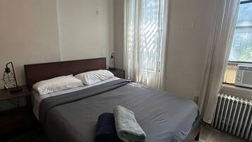 A bedroom with a large bed, a bedside table with a lamp, and a radiator.