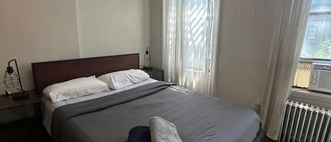 Une chambre à coucher avec un grand lit, une table de chevet avec une lampe et un radiateur.
